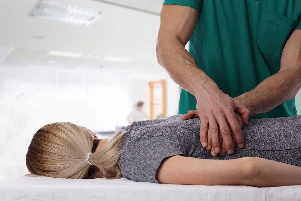 Person gently massaging the jaw while seated at a desk with relaxed shoulders and an upright neck.