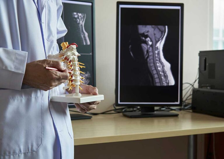 Chiropractor assessing a patient’s posture beside a massage table in a bright treatment room.