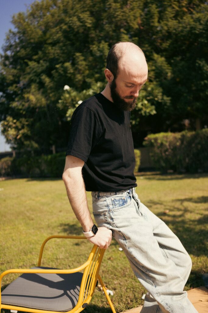 Adult performing gentle mobility exercises beside a sturdy chair in a bright home.