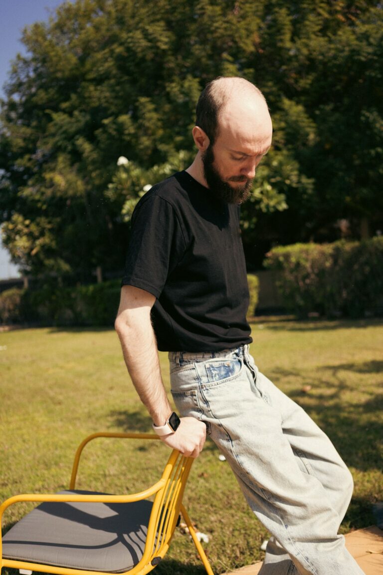 Adult performing gentle mobility exercises beside a sturdy chair in a bright home.
